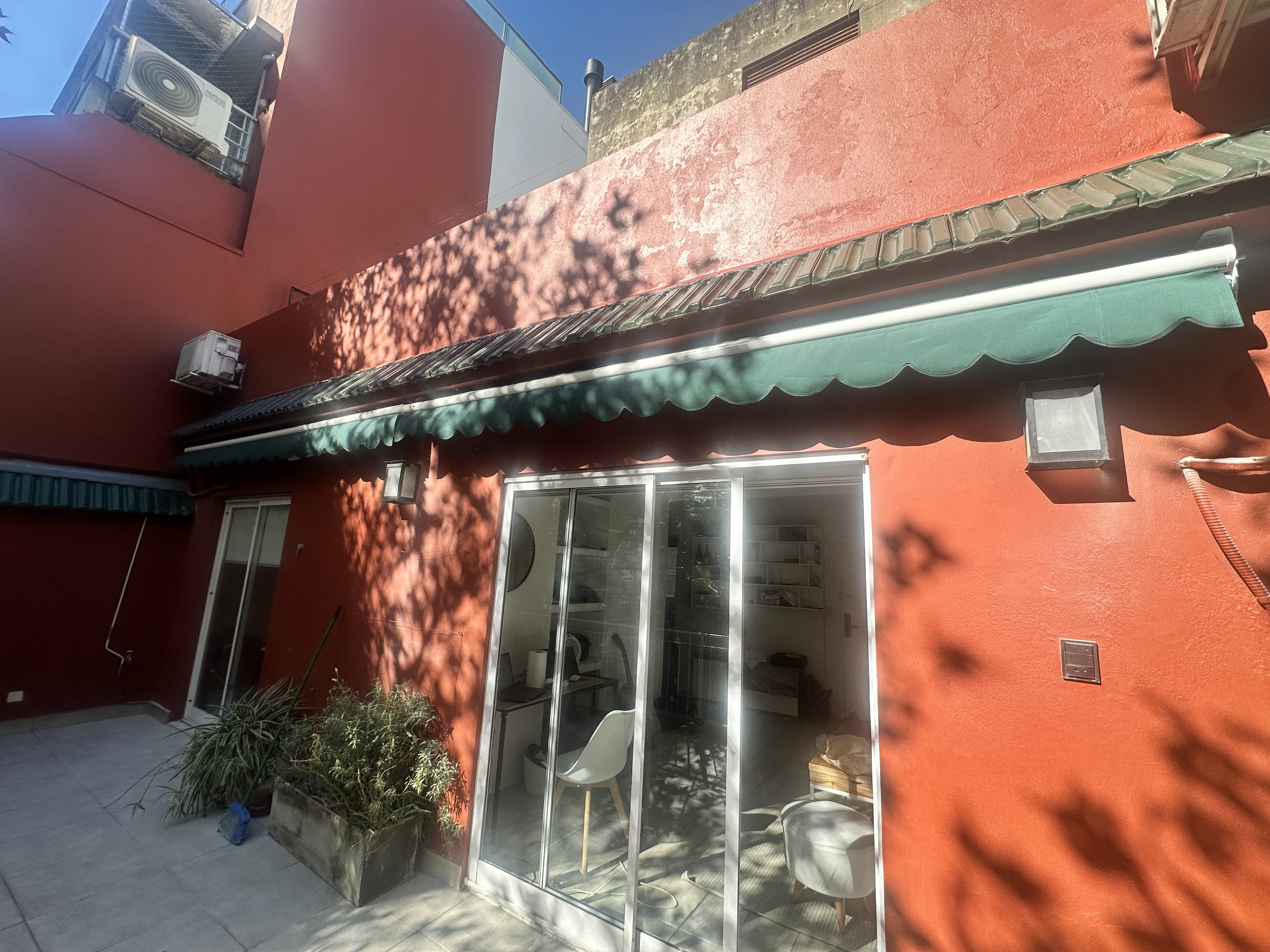 Terracotta exterior wall with green awning and sliding doors to the apartment